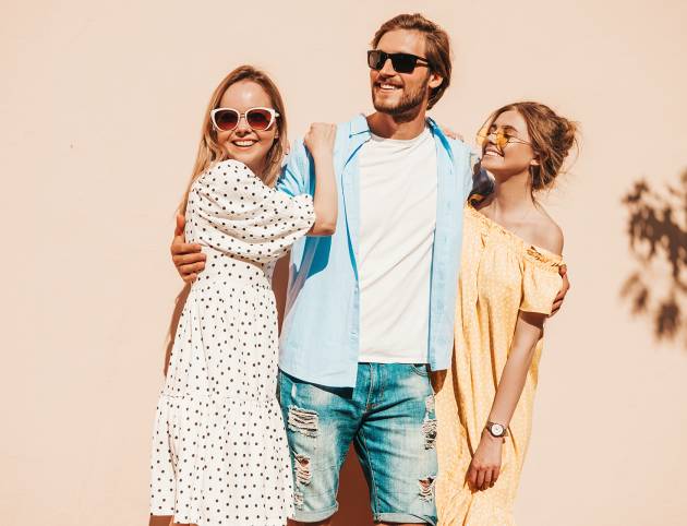 Group of young three stylish friends posing in the street. Fashion man and two cute girls